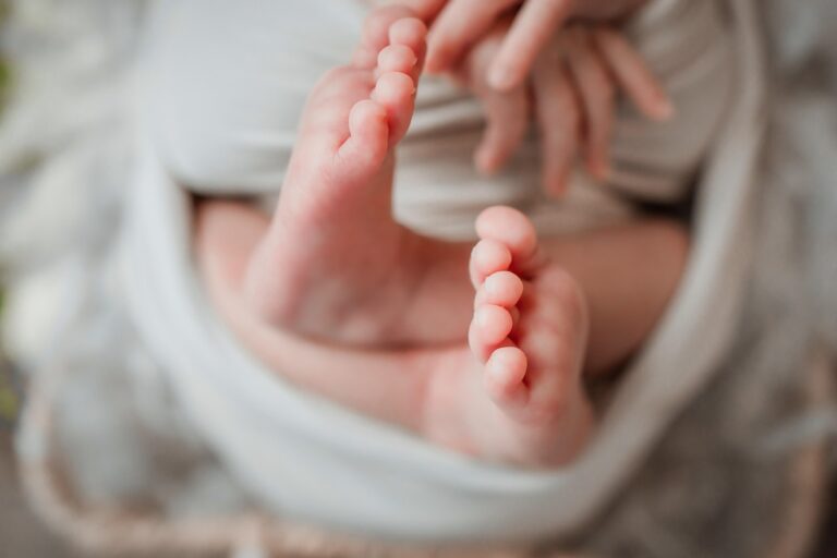 Neugeborene Babyfüße nach Kaiserschnitt auf weißer Windel