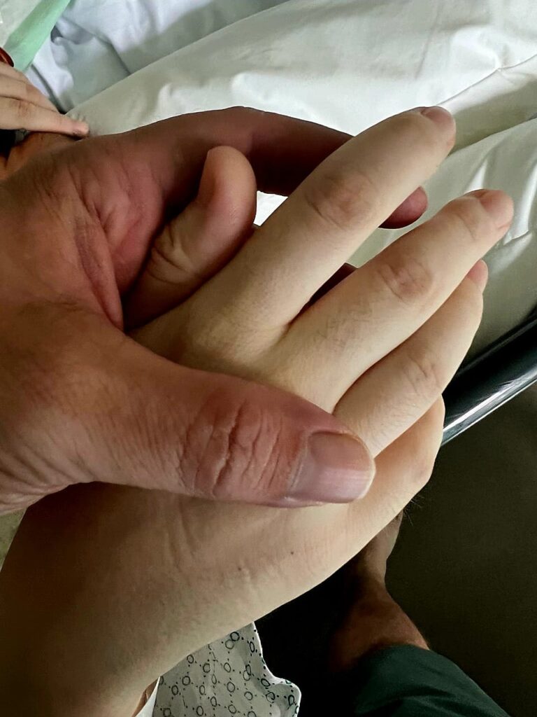 Blasse Hand nach Kaiserschnitt, von Partner gehalten