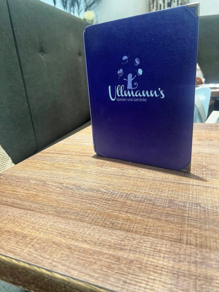 Menükarte von Ullmanns Zuckerbäckerei Wien stehend auf einem Tisch.