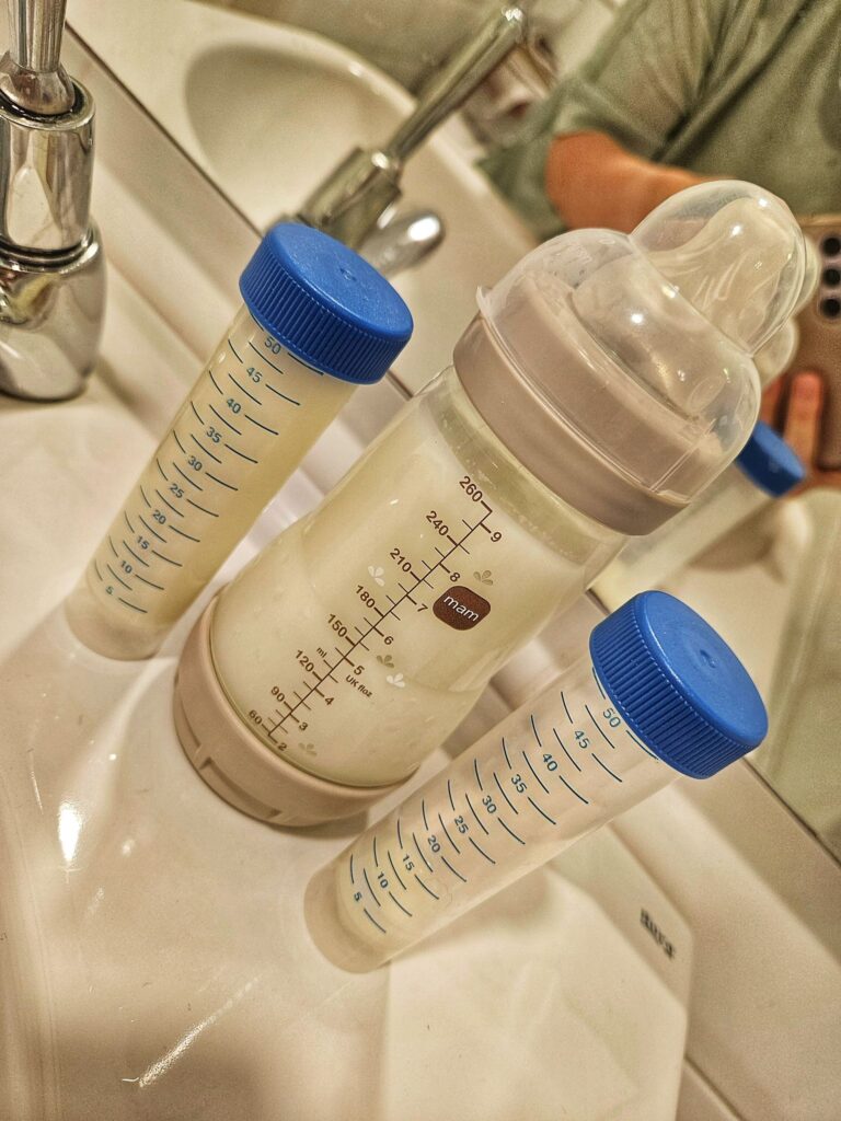 Eine volle Milchflasche mit zwei danebenliegenden Falcon Tubes, gefüllt mit Muttermilch