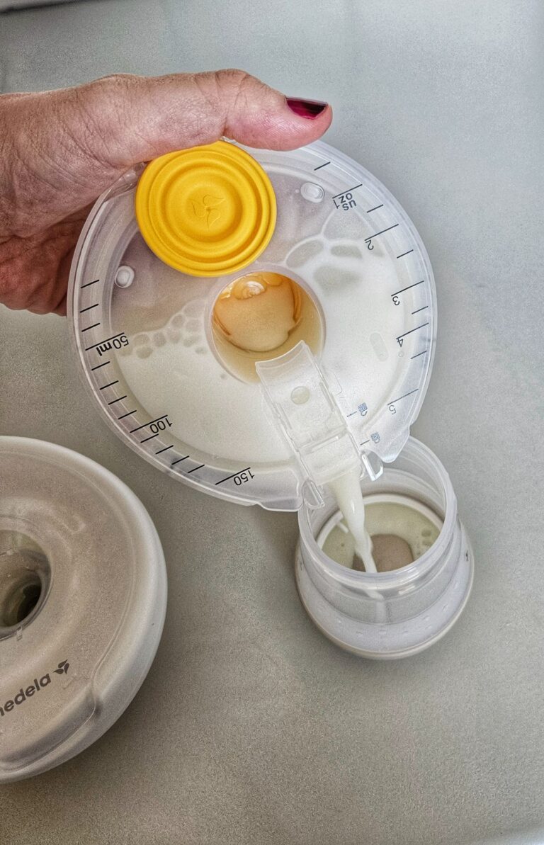 Milch wird aus einer gefüllten Medela Magic Inbra in eine Babyflasche gegossen