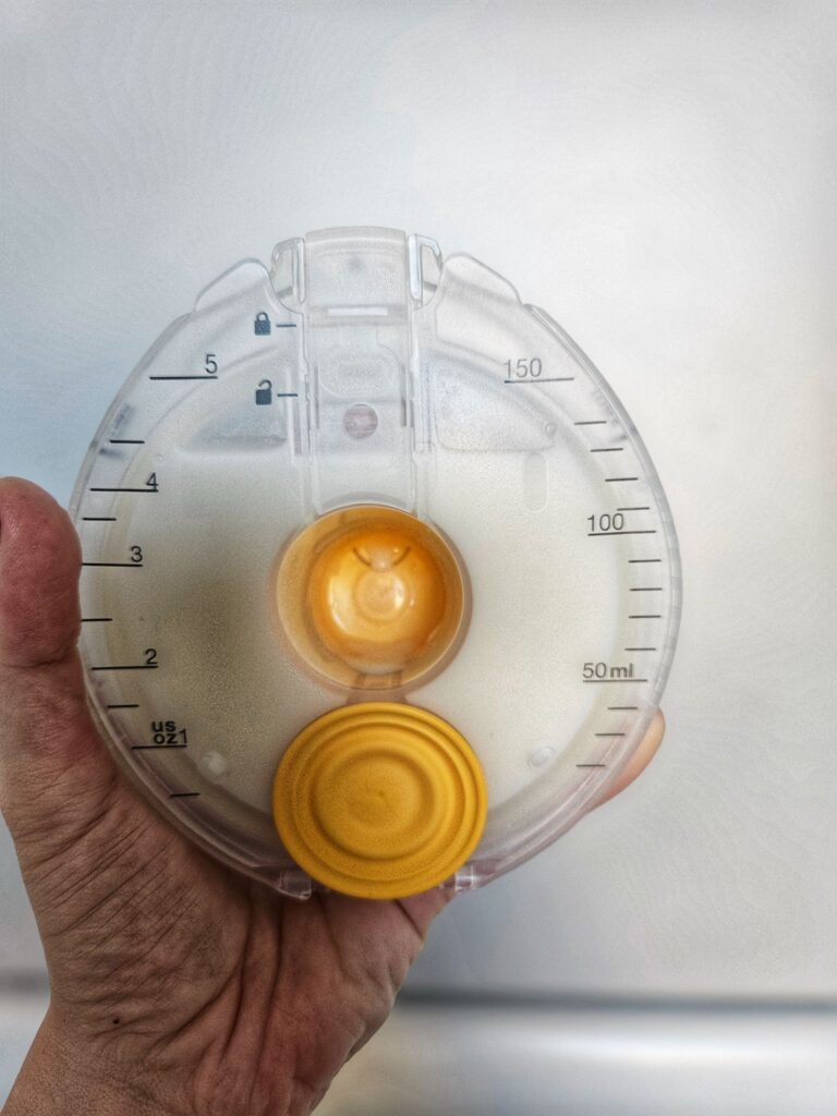 Innenansicht eines abgekoppelten, mit Milch gefüllten Milchbehälters der Medela Magic Inbra.