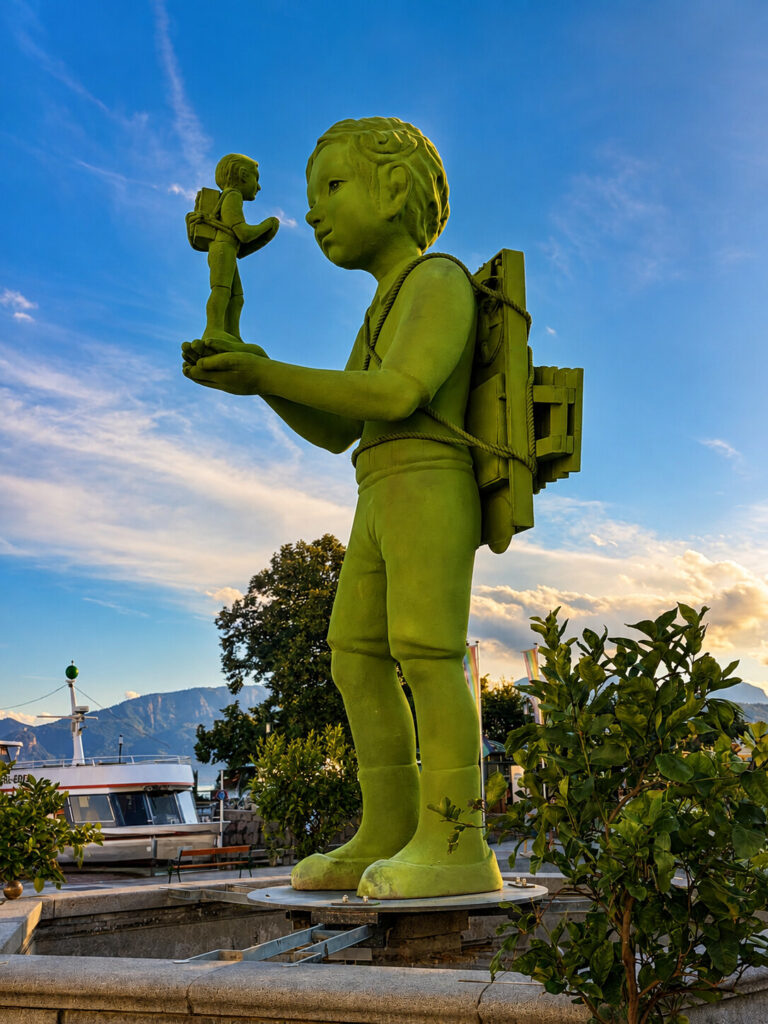 Grüner Riese mit kleiner Figur auf der Hand am Rathausplatz in Gmunden